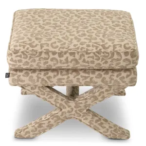 Taburete otomano de tela estampada en color beige con asiento acolchado y base en forma de cruz - Mobiliario de lujo para hoteles Vista lateral por Luxury Group International