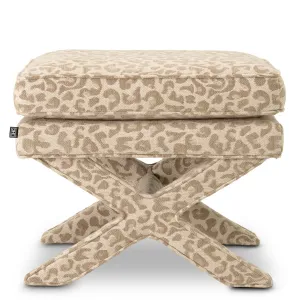 Taburete otomano de tela estampada en color beige con asiento acolchado y base en forma de cruz - Mobiliario de lujo para hoteles Vista lateral por Luxury Group International