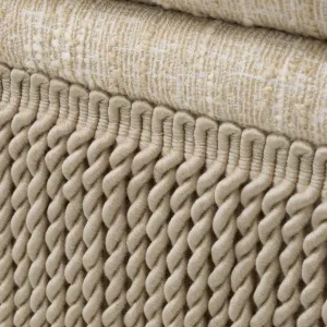 Taburete otomano de tela con textura cremosa, base con flecos y cojín mullido - Taburete de lujo Vista detalle por Luxury Group International