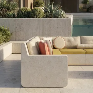 Canapé d'angle d'extérieur en béton beige de luxe avec coussins orange coucher de soleil - Mobilier d'extérieur Vue lifestyle par Luxury Group International