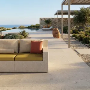 Canapé d'angle d'extérieur en béton beige de luxe avec coussins orange coucher de soleil - Mobilier d'extérieur Vue lifestyle par Luxury Group International
