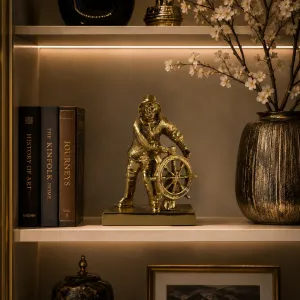 Luxus Maritime Steuermann-Bronzeskulptur mit Schiffsrad in Gold- und Oxidfinish Lifestyle-Ansicht von Luxury Group International
