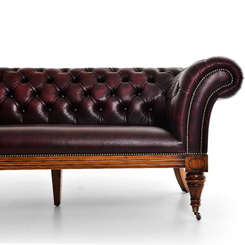 Sofá Chesterfield de Lujo en Cuero Burdeos con Respaldo Profundamente Capitoneado y Patas con Ruedas de Latón Vista detalle por Luxury Group International