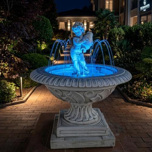 Luxury Illuminated Baroque Cherub Water Fountain with Circular Sculpted Basin & Pedestal Base - Baroque Fountain Lifestyle View by Luxury Group International