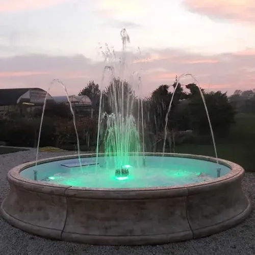 Luxus Barockbrunnen mit Steinoptik, beleuchtetem Mittelstrahl & radialen Bogenfontänen – Barockbrunnen Lifestyle-Ansicht von Luxury Group International