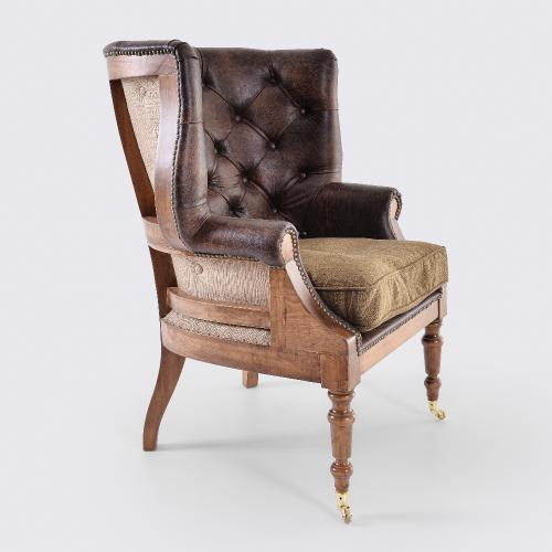 Sillón de cuero capitoné de lujo con estructura de madera de respaldo abierto y patas con ruedas de latón Vista lateral por Luxury Group International